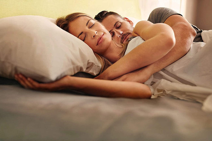 Man and woman laying in bed with cream sheets